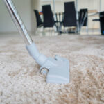 Close up of a vacuum cleaner being used while removing dirt on white carpet
