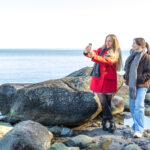 Two women walking on the seashore. Two friends enjoying and spending time together.