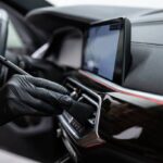 car detailing studio employee carefully cleans the air vents with a brush