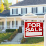 Home For Sale Real Estate Sign in Front of Beautiful New House.