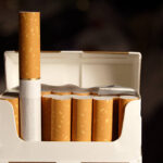 Opened pack of cigarettes. One standing out. Selective focus.