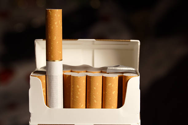 Opened pack of cigarettes. One standing out. Selective focus.