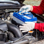 a car mechanic installs a battery in a car. Battery replacement and repair.