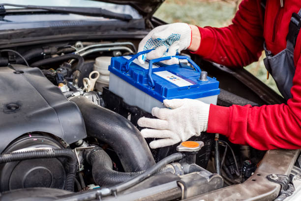 a car mechanic installs a battery in a car. Battery replacement and repair.