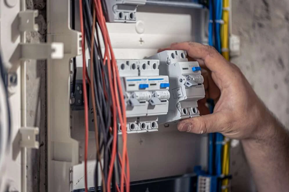 male-electrician-works-switchboard-with-electrical-connecting-cable_169016-15086